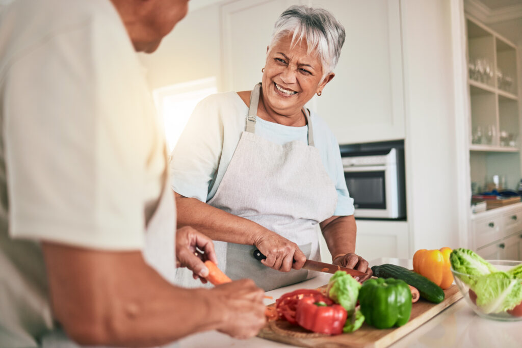 Elderly couple cooking and laughing together as they prepare a nutritious meal