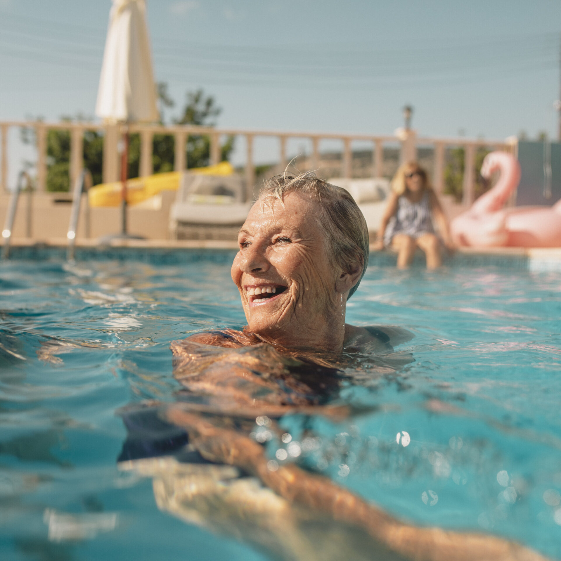 An older woman is enjoying a swim in beautiful weather with friends on a holiday, being active enjoying a Healthy Weight For Life.