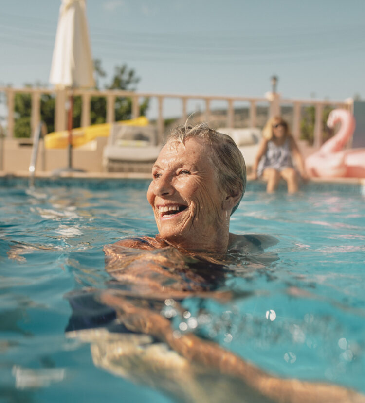 An older woman is enjoying a swim in beautiful weather with friends on a holiday, being active enjoying a Healthy Weight For Life.